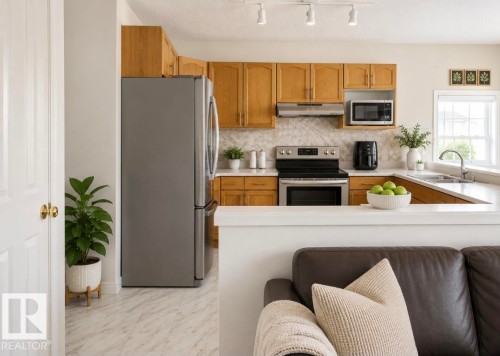 Kitchen with wood-finish cabinetry, stainless steel appliances, white countertops, and a patterned backsplash - 3236 27 Avenue Nw, Edmonton, AB - Indoor Photo Showing Kitchen With Double Sink