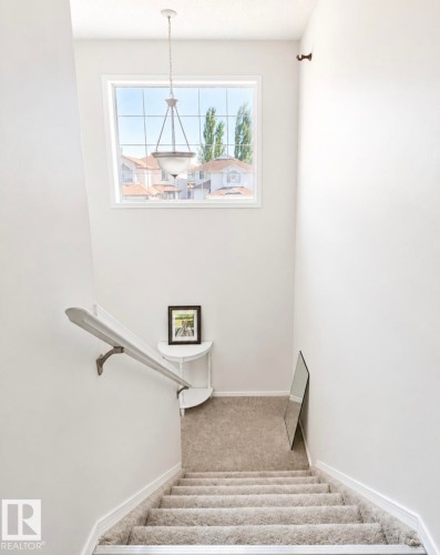 High-ceiling staircase featuring a large upper window, a white painted handrail, and carpeted stairs with metal treads - 3236 27 Avenue Nw, Edmonton, AB - Indoor Photo Showing Other Room