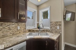 Corner kitchen sink featuring a gooseneck faucet, dual basin, and light-toned countertop - 