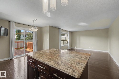 Spacious open-concept living area featuring wood-finish flooring, a kitchen island with a stone countertop, and recessed lighting - 1047 Leger Boulevard Nw, Edmonton, AB - Indoor Photo Showing Kitchen