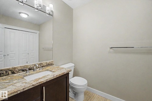 Bathroom vanity featuring a polished stone countertop with an integrated sink and chrome fixtures - 1047 Leger Boulevard Nw, Edmonton, AB - Indoor Photo Showing Bathroom