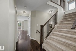 Carpeted staircase with dark wood handrail and black wrought iron balusters - 