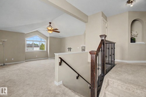 Carpeted upper-level space featuring a vaulted ceiling and a decorative window - 1047 Leger Boulevard Nw, Edmonton, AB - Indoor Photo Showing Other Room