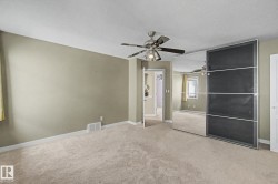 Carpeted room featuring a ceiling fan with integrated lighting, mirrored closet doors, and light neutral wall paint - 