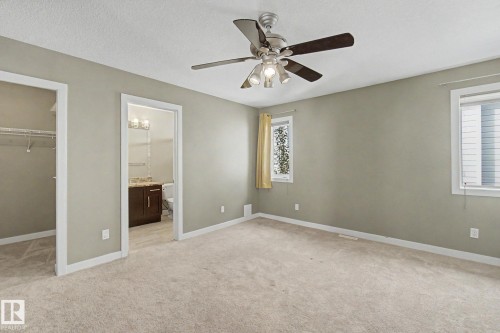 Spacious room featuring neutral carpeting, light neutral wall color, and a ceiling fan with integrated lighting - 1047 Leger Boulevard Nw, Edmonton, AB - Indoor Photo Showing Other Room