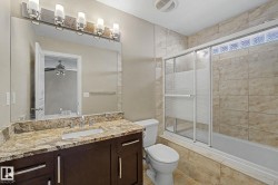 Full bathroom featuring a dark wood vanity with a stone countertop, an integrated sink, and a large mirror - 