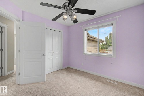 Carpeted interior space featuring a window with blinds, a ceiling fan with integrated lighting, and a bi-fold closet door - 1047 Leger Boulevard Nw, Edmonton, AB - Indoor Photo Showing Other Room