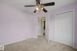 Bedroom featuring light purple walls, neutral carpet flooring, and a ceiling fan with integrated lighting - 