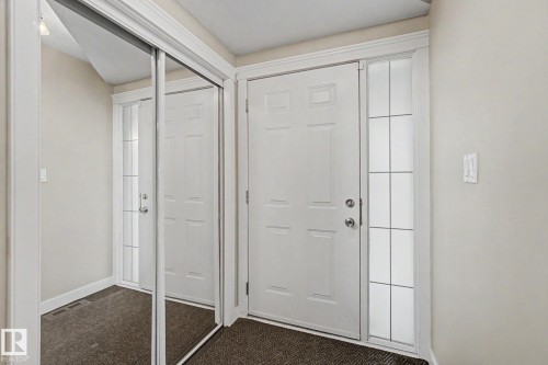 Entryway featuring a paneled door with a sidelight, mirrored sliding closet doors, and neutral wall tones - 1047 Leger Boulevard Nw, Edmonton, AB - Indoor Photo Showing Other Room