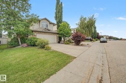 Front exterior with attached garage, beige siding, brick accents, and a sloped roofline - 