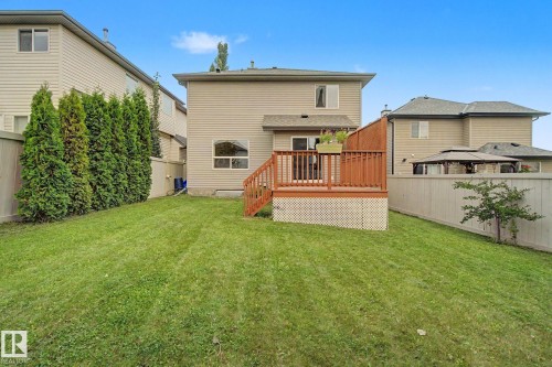 Spacious backyard featuring a large lawn, wood deck with lattice skirting, and mature perimeter trees - 1047 Leger Boulevard Nw, Edmonton, AB - Outdoor With Deck Patio Veranda With Exterior