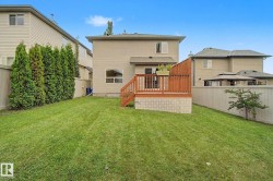 Spacious backyard featuring a large lawn, wood deck with lattice skirting, and mature perimeter trees - 