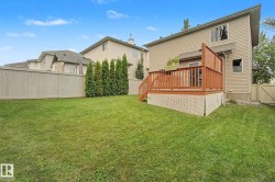 Spacious backyard featuring a large elevated deck with wood railings, lattice skirting, and privacy screen - 