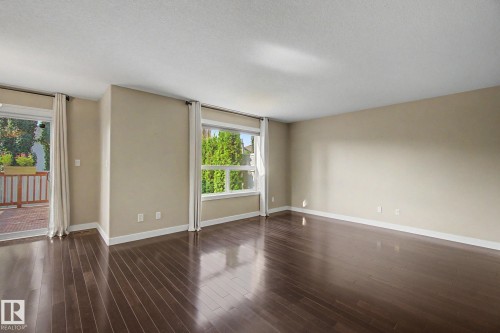 Expansive room featuring dark wood-finish flooring, light neutral-toned walls, and white trim - 1047 Leger Boulevard Nw, Edmonton, AB - Indoor Photo Showing Other Room