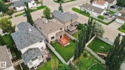 Expansive backyard featuring a manicured lawn, wood-stained deck, and mature trees - 