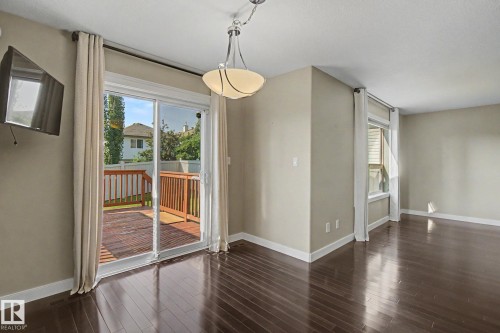 Spacious room featuring rich wood-finish flooring, neutral wall tones, and white trim - 1047 Leger Boulevard Nw, Edmonton, AB - Indoor Photo Showing Other Room