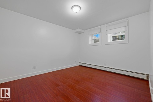 Room featuring wood-finish flooring, white baseboards, and neutral wall paint - #3 9955 114 St Nw, Edmonton, AB - Indoor Photo Showing Other Room