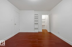 Room featuring wood-finish flooring, white painted walls, and white baseboards - 