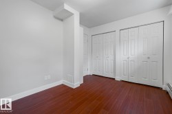 Room featuring wood-finish flooring and multiple built-in storage closets with bi-fold doors - 