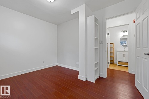 Bright interior room featuring wood-finish flooring and a built-in shelving unit - #3 9955 114 St Nw, Edmonton, AB - Indoor Photo Showing Other Room
