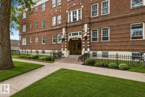 Brick facade building with white trim, featuring an ornate entry with a transom window and sconce lighting - #3 9955 114 St Nw, Edmonton, AB - Outdoor