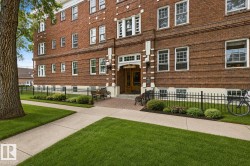 Brick facade building with white trim, featuring an ornate entry with a transom window and sconce lighting - 