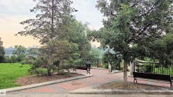 Terraced outdoor space featuring a paved pathway, mature trees, and a distant cityscape - 