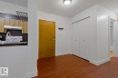 Foyer area featuring wood-finish flooring, a solid-core entry door, and a flush-mount ceiling light - #3 9955 114 St Nw, Edmonton, AB  - Indoor 
