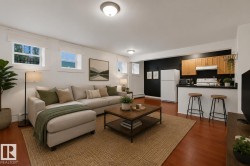 Open-concept living space featuring wood-finish flooring, recessed windows, an integrated kitchen area with wood cabinetry, and a black countertop bar - 