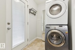 Dedicated laundry area with stacked front-loading washer and dryer, tile flooring, and light gray wall paint - 