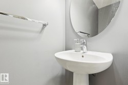 White porcelain pedestal sink with a chrome faucet and an oval wall-mounted mirror - 