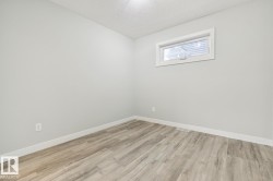 Spacious room featuring light gray walls, wood-finish flooring, white baseboards, and a contemporary window with white trim - 