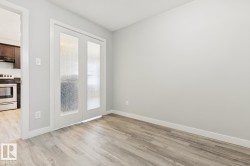 Spacious room featuring wood-finish flooring, light gray wall tones, and white baseboards - 