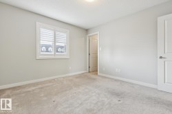 Neutral-toned room featuring a window with white plantation shutters, light-colored carpet, and crisp white trim - 