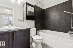 Bathroom featuring a dark wood-finish vanity with a single sink and a gray countertop - 