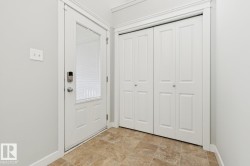 Entryway featuring a white door with a glass insert and digital lock, bifold closet doors, and patterned tile flooring - 