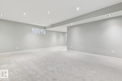 Spacious room featuring light gray carpeting, recessed ceiling lighting, a single window with blinds, and white baseboards - 