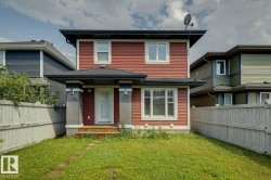 Two-story home featuring red siding, white trim, and a dark roof - 