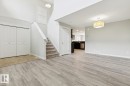Open-concept living space with light wood-finish flooring, a contemporary overhead light fixture, and a staircase featuring carpeted treads - 4058 Morrison Way Nw, Edmonton, AB  - Indoor Photo Showing Other Room 