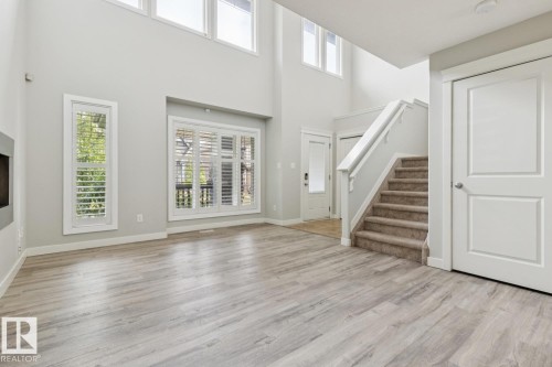 Spacious open room featuring wood-finish flooring, high ceilings, and multiple windows with plantation shutters - 4058 Morrison Way Nw, Edmonton, AB - Indoor Photo Showing Other Room