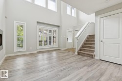 Spacious open room featuring wood-finish flooring, high ceilings, and multiple windows with plantation shutters - 