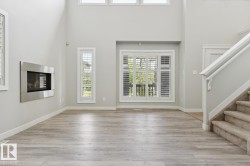 Spacious interior featuring high ceilings, wood-finish flooring, and a contemporary wall-mounted fireplace - 