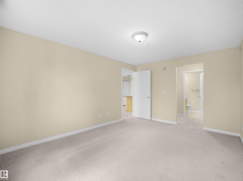 Carpeted interior space with light-toned walls and white trim - #220 245 Edwards Dr Sw, Edmonton, AB - Indoor Photo Showing Other Room