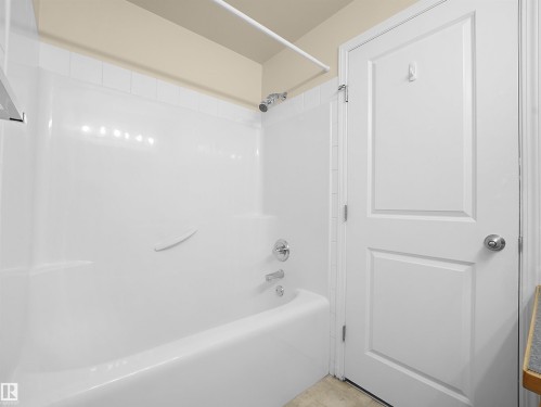 White bathtub and shower combination unit featuring a showerhead and tub spout with chrome finishes - #220 245 Edwards Dr Sw, Edmonton, AB - Indoor Photo Showing Bathroom