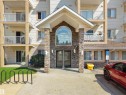 Multi-story residential building featuring a stone-clad entryway with an arched window - #220 245 Edwards Dr Sw, Edmonton, AB  - Outdoor With Balcony With Facade 