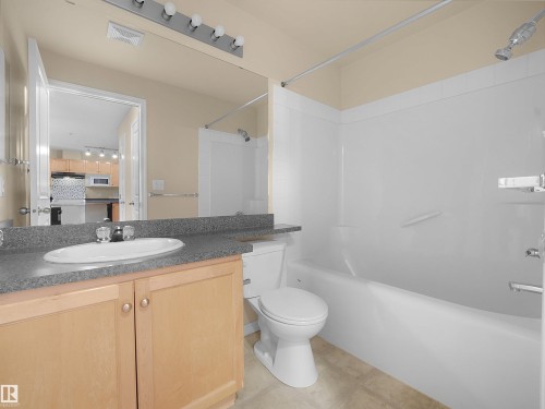 Bathroom featuring a light wood-finish vanity with a laminate countertop, an oval undermount sink, and a chrome faucet - #220 245 Edwards Dr Sw, Edmonton, AB - Indoor Photo Showing Bathroom