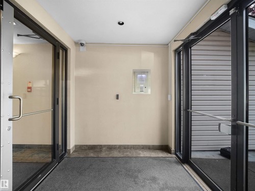 Entryway featuring double glass doors with metal frames and handles, recessed ceiling lighting, a security camera, and a tiled threshold - #220 245 Edwards Dr Sw, Edmonton, AB -  Photo Showing Other Room