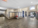 Spacious building lobby featuring tiled flooring, a bank of mailboxes with a stone-finish counter, and a vaulted ceiling with an arched transom window - #220 245 Edwards Dr Sw, Edmonton, AB  - Indoor Photo Showing Other Room 