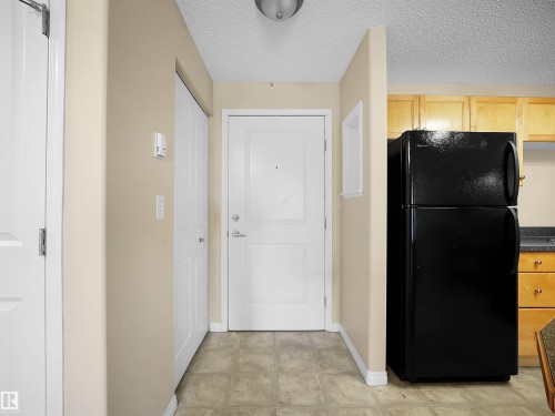 Hallway entry featuring neutral taupe walls, white trim, and neutral-tone tile flooring - #220 245 Edwards Dr Sw, Edmonton, AB - Indoor Photo Showing Other Room