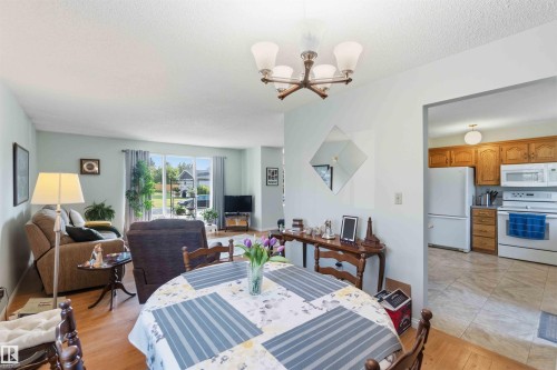 Dining area with wood-finish flooring, a multi-bulb chandelier, and an archway opening to the kitchen - 30 Cavanagh Crescent, Stony Plain, AB - Indoor Photo Showing Dining Room